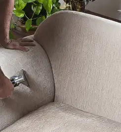 Professional upholstery cleaner deep-cleaning a fabric sofa with a handheld extraction tool and hose Tampa, FL.